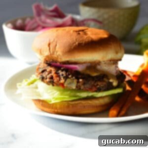A perfectly cooked chipotle black bean burger served on a toasted bun with a generous side of golden sweet potato fries, highlighting its appetizing appearance and crispy texture.