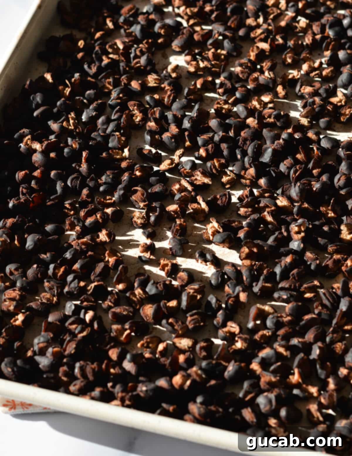 Close-up of perfectly baked black beans on a sheet pan, showing their slightly dried but still tender texture, ideal for crafting firm black bean burger patties.
