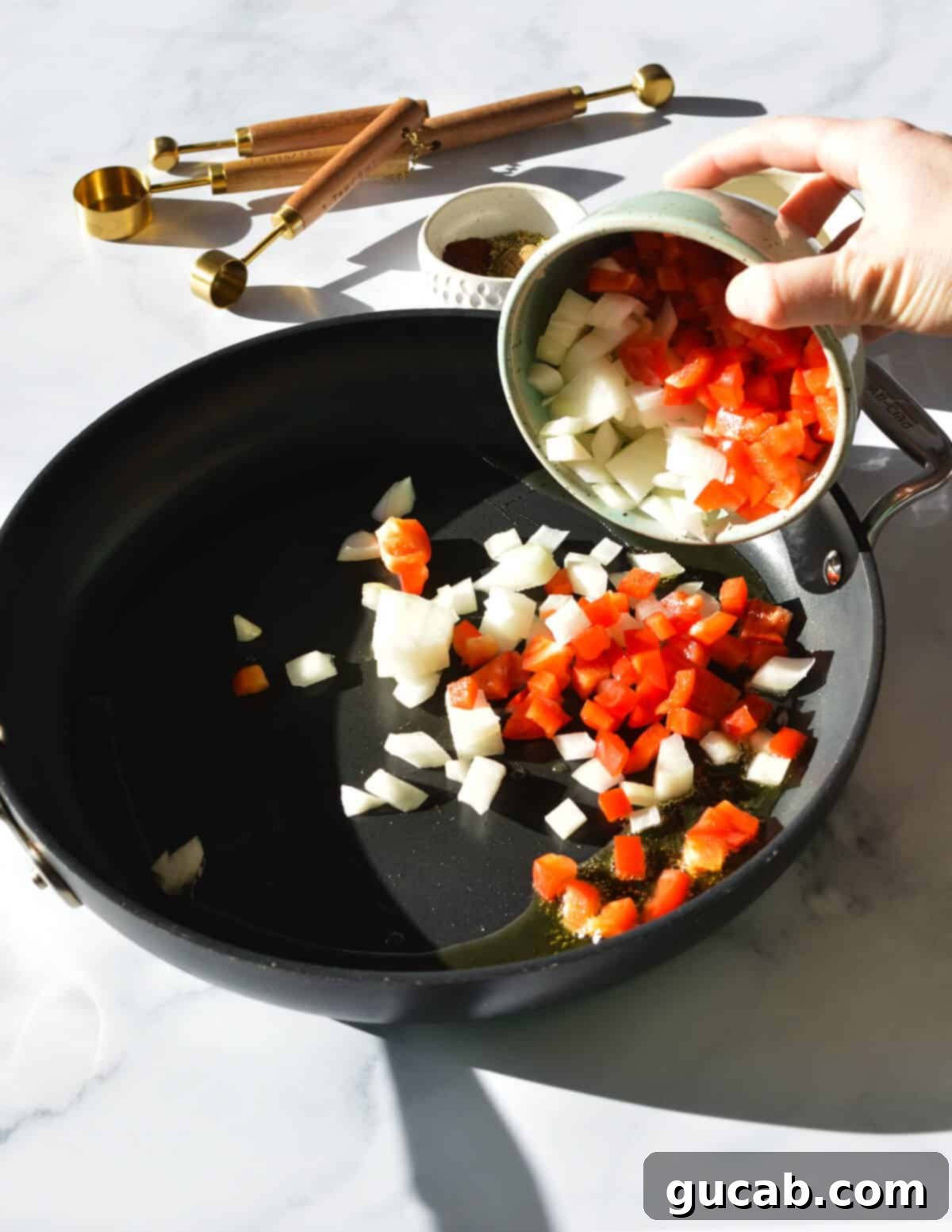 Diced red bell pepper and sweet onion in a nonstick skillet, starting to soften and caramelize, forming a flavorful base for the black bean burgers.