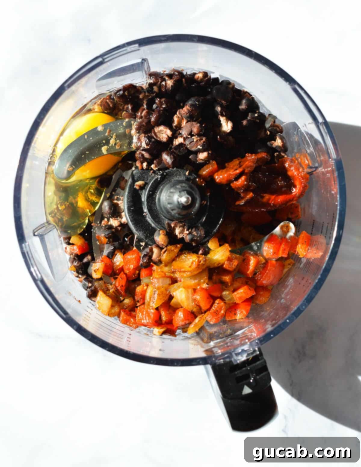 Dried black beans combined with half of the sautéed red pepper and onion mixture in a large bowl, forming the base for the black bean burger patties before adding the processed ingredients.