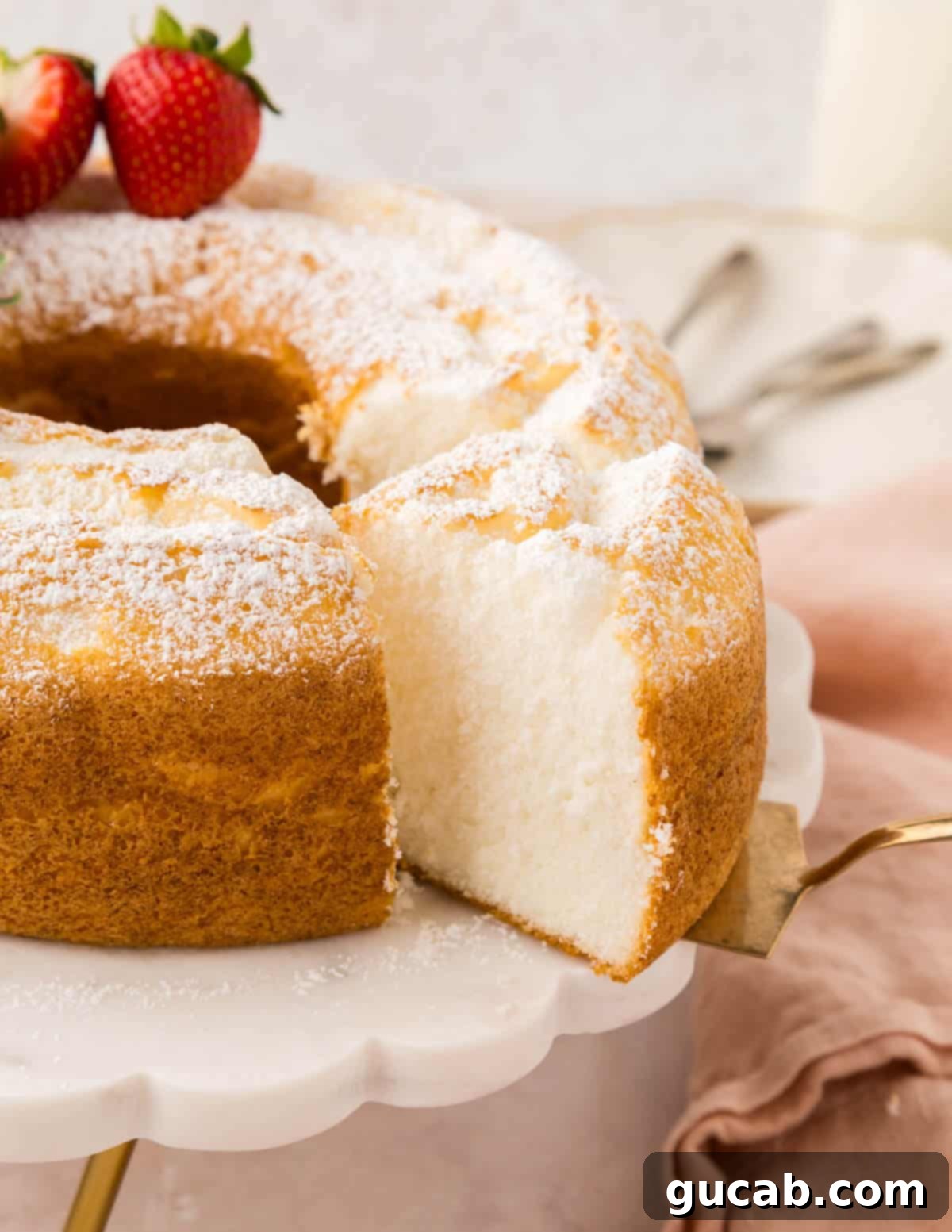 Whole homemade angel food cake on a white cake stand, ready to be served.