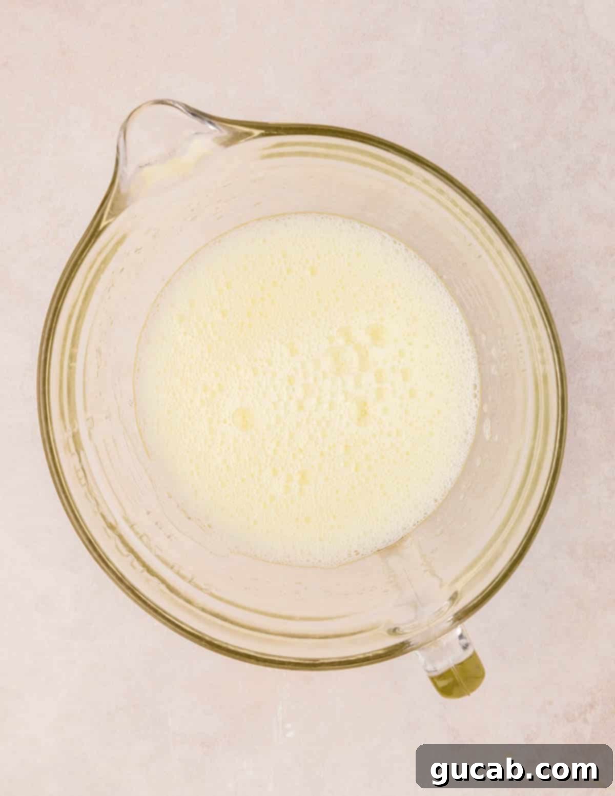 Frothy egg whites with cream of tartar and salt beginning to whip in a clean mixing bowl.