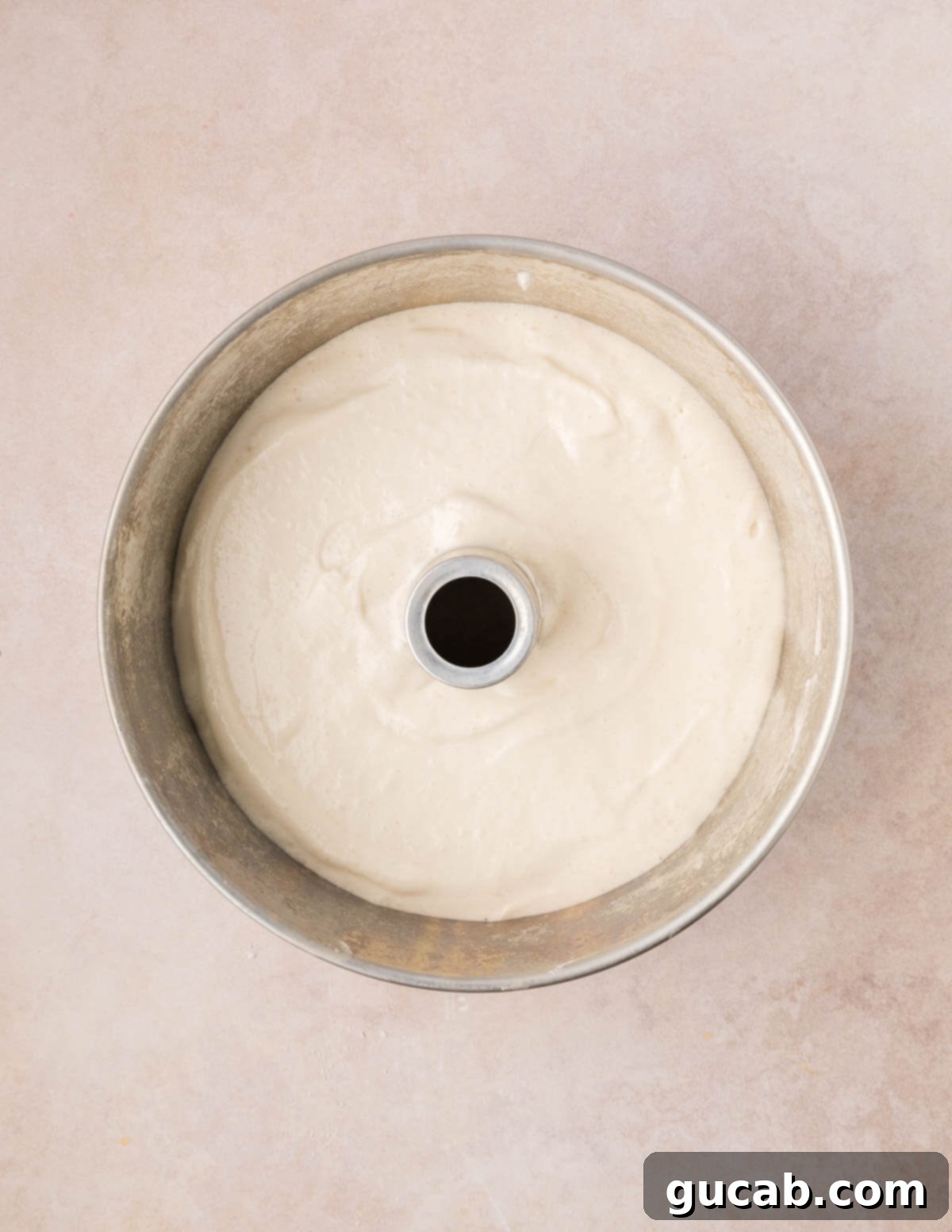 Unbaked angel food cake batter smoothed into a tube pan, ready for the oven.