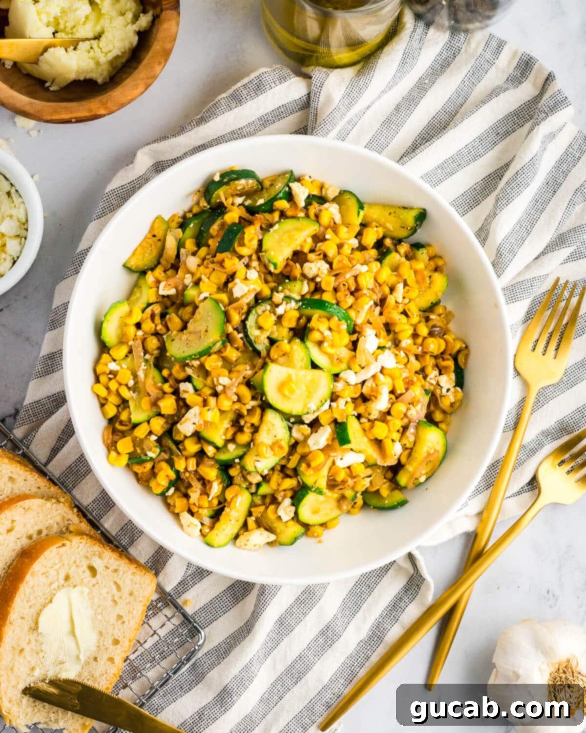 A vibrant bowl of sauteed corn, zucchini, crumbled feta, and shallots, ready to be served.