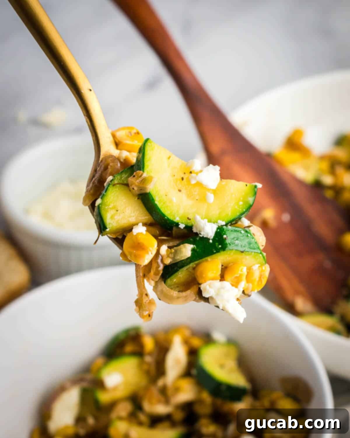 A fork holding a perfect bite of sauteed zucchini, caramelized corn, and shallots, showcasing the texture and vibrant colors.