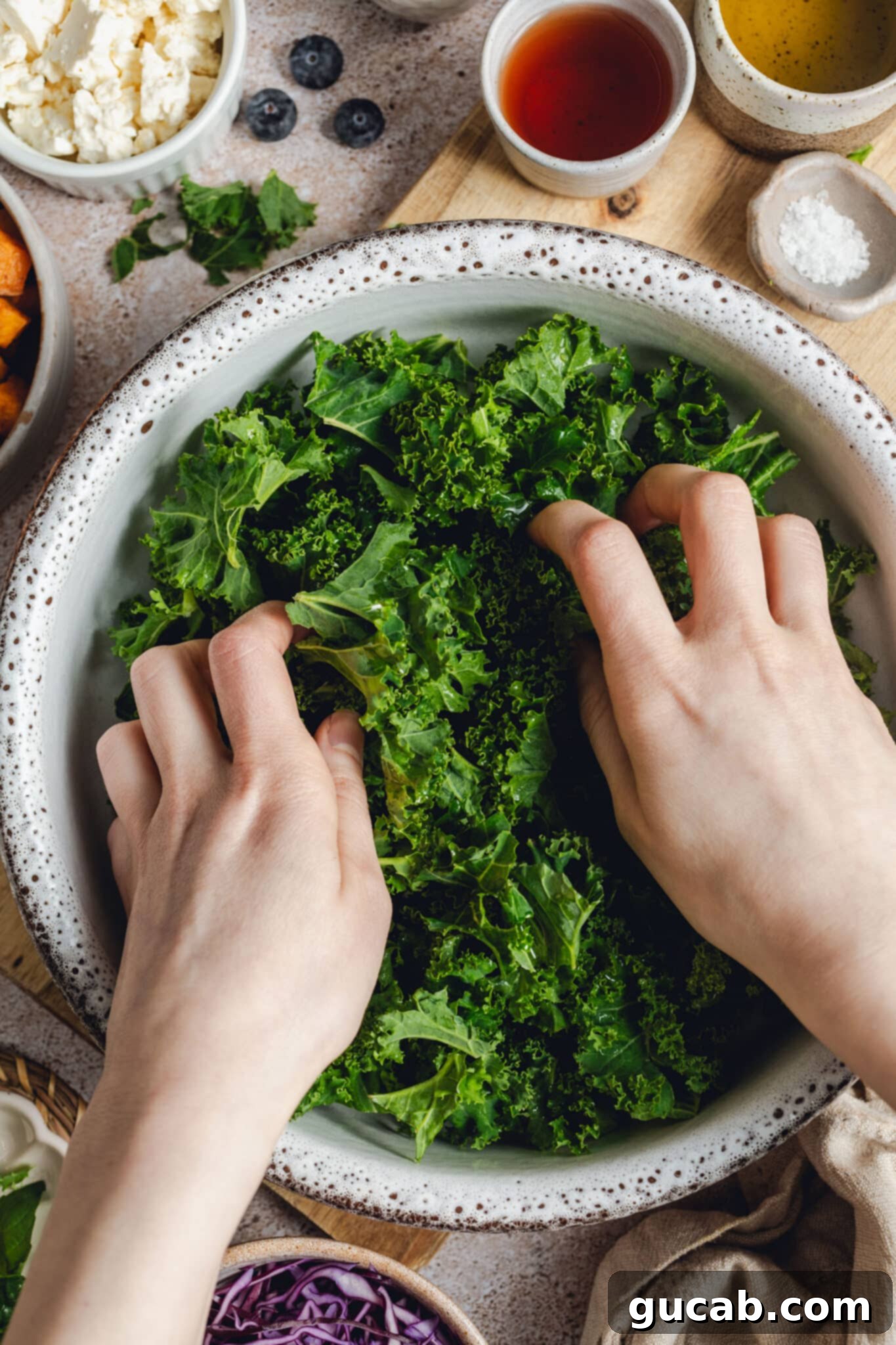 hands massaging olive oil into kale leaves.
