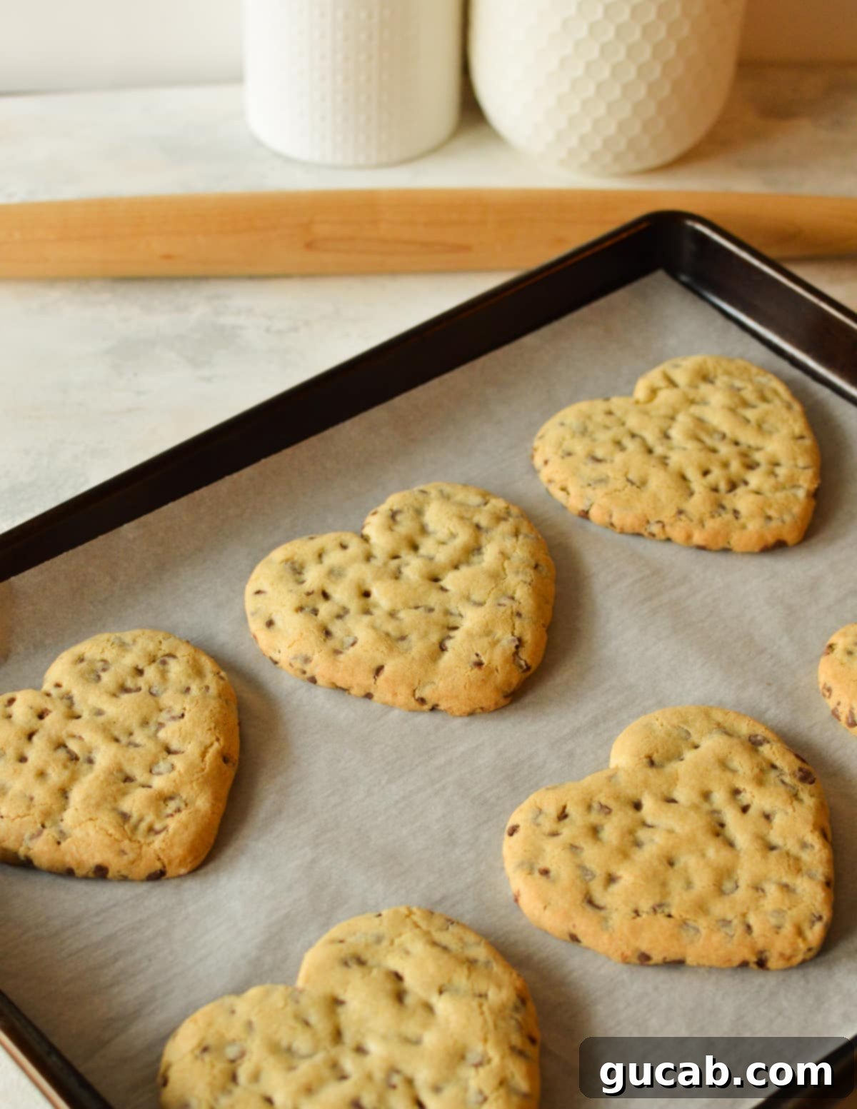17 Heartwarming Valentine's Day Desserts 3 chocolate chip cookies decorated for Valentine's Day on a sheet pan.