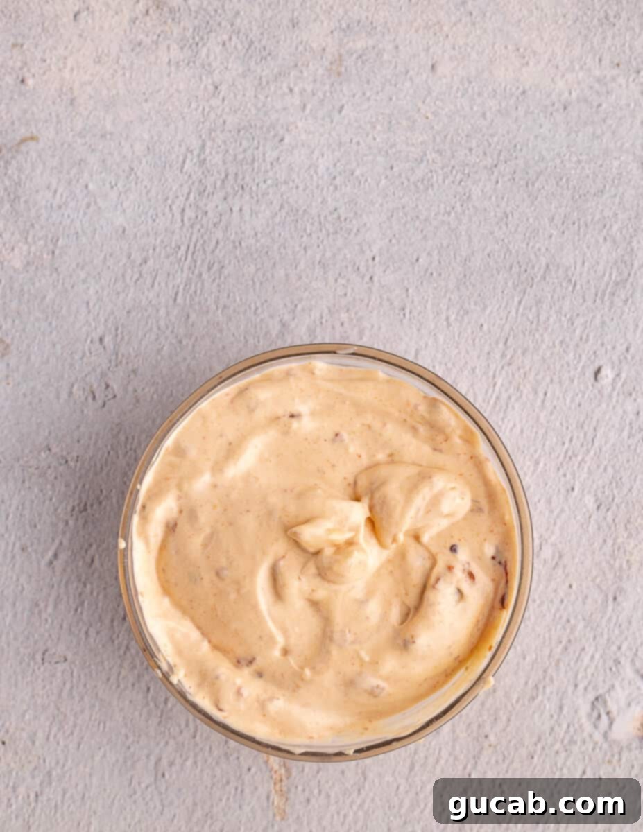 A close-up view of the perfectly blended chipotle mayo in the food processor, showcasing its vibrant color and smooth consistency.