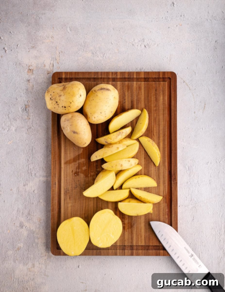 Gold potatoes expertly cut into uniform wedges on a cutting board, ready for soaking.