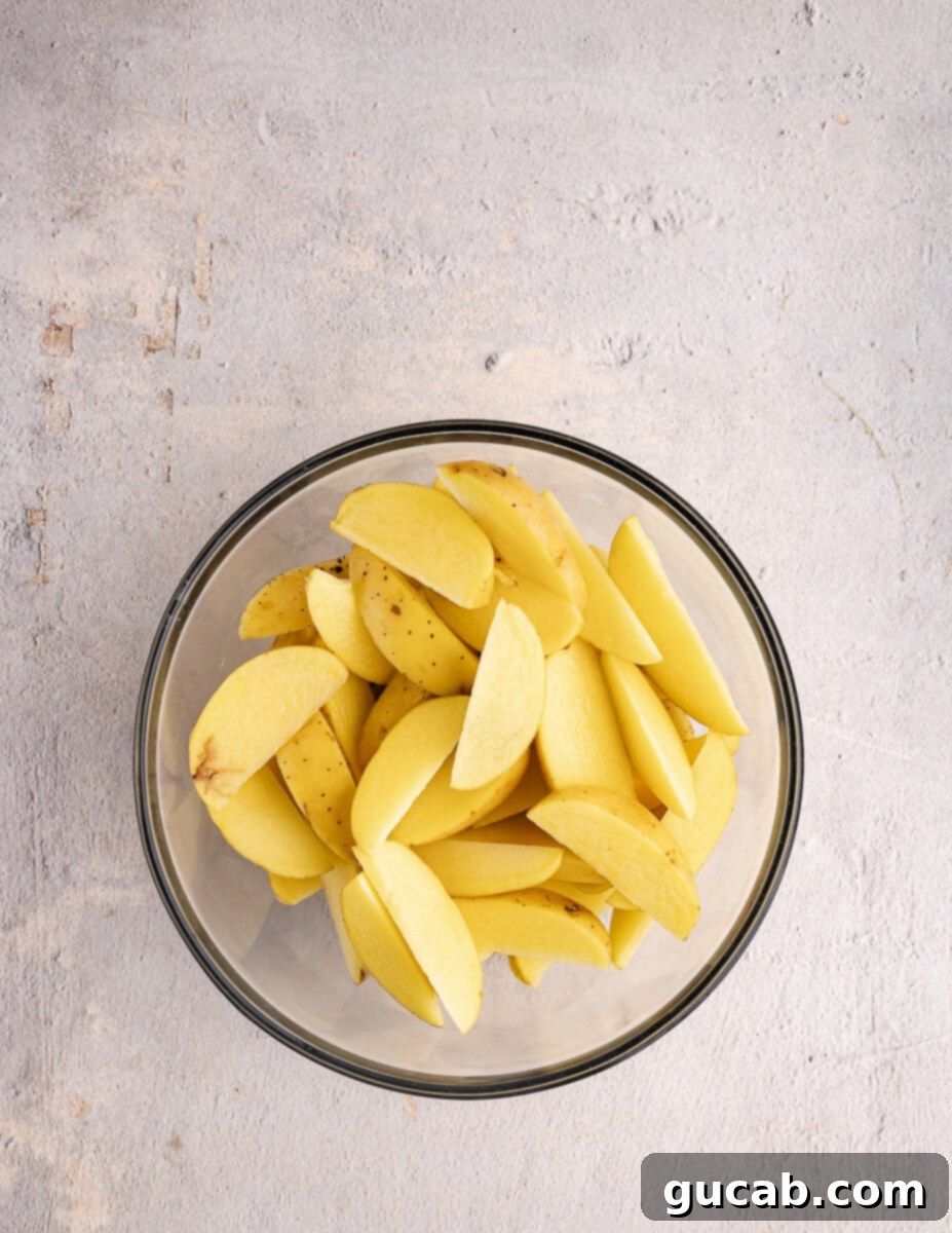 A bowl filled with freshly cut gold potato wedges, showcasing their even size and readiness for the next step.