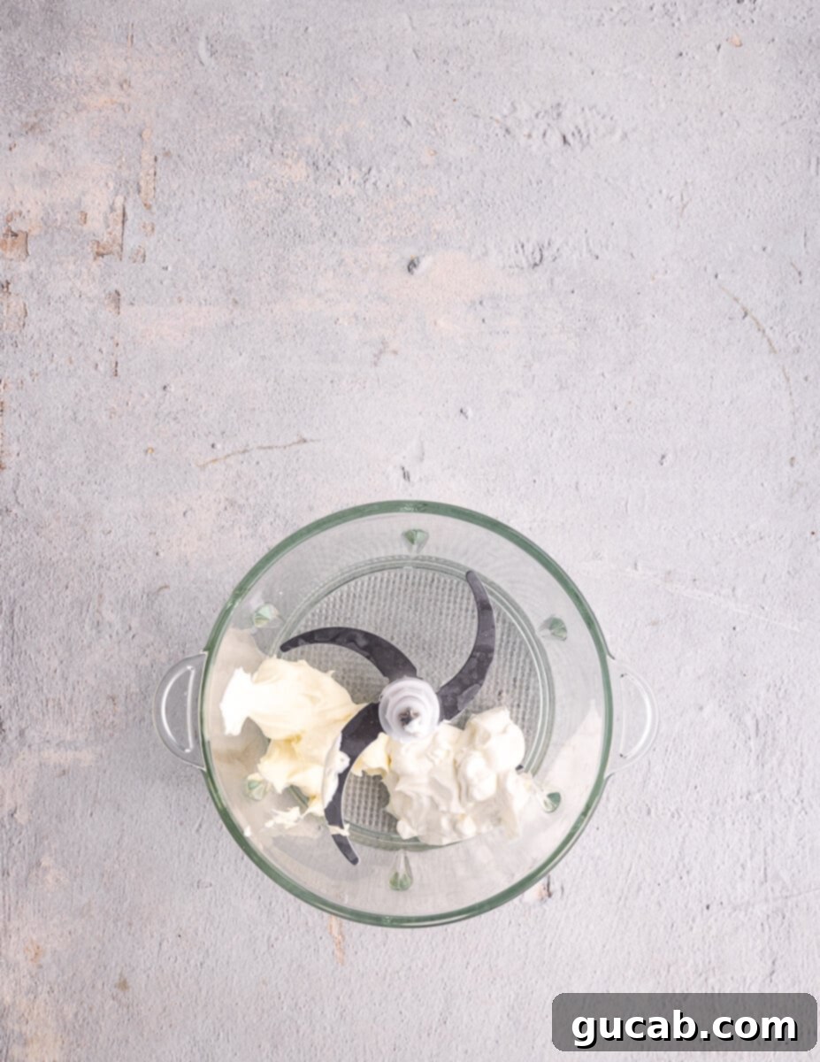 Sour cream and mayonnaise are measured into a food processor, forming the creamy base for the chipotle sauce.