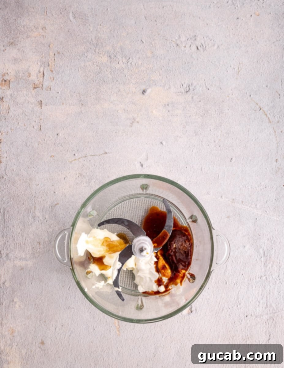 Sour cream, mayonnaise, and chipotle in adobo peppers are added to a food processor, ready to be blended into a flavorful sauce.