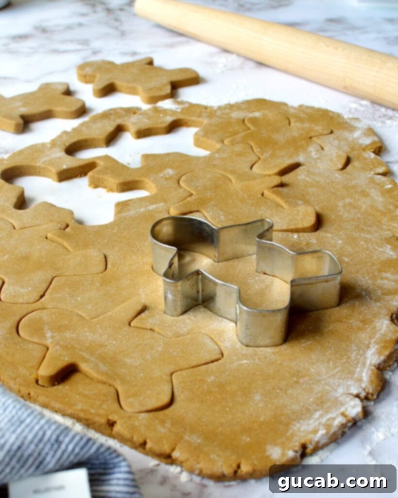 Melt-in-Your-Mouth Gluten-Free Gingerbread Cookies 3 Gluten-free gingerbread cookie dough being cut into festive gingerbread men and snowflake shapes.