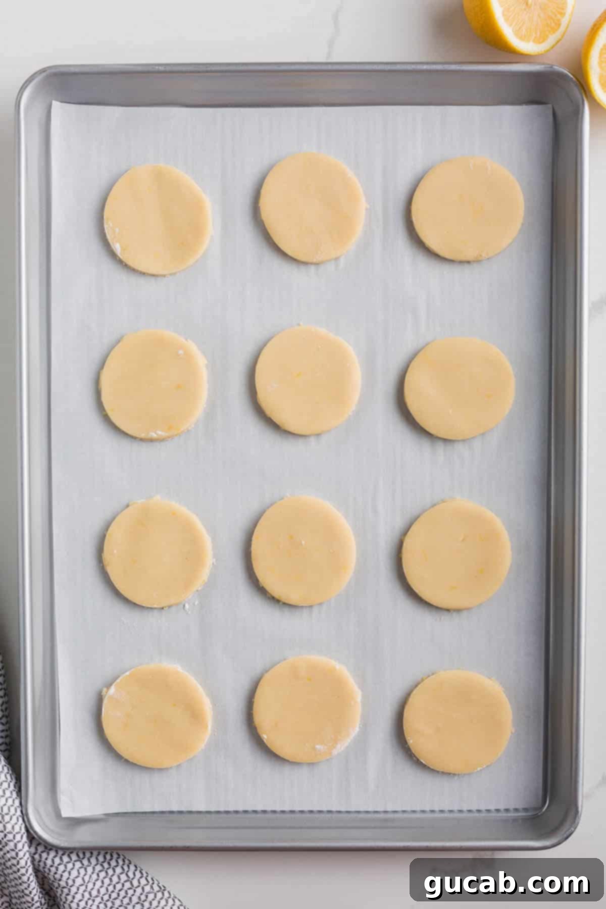 Sweet and Zesty Lemon Cookies 9 sugar cookie dough circles on a sheet pan.