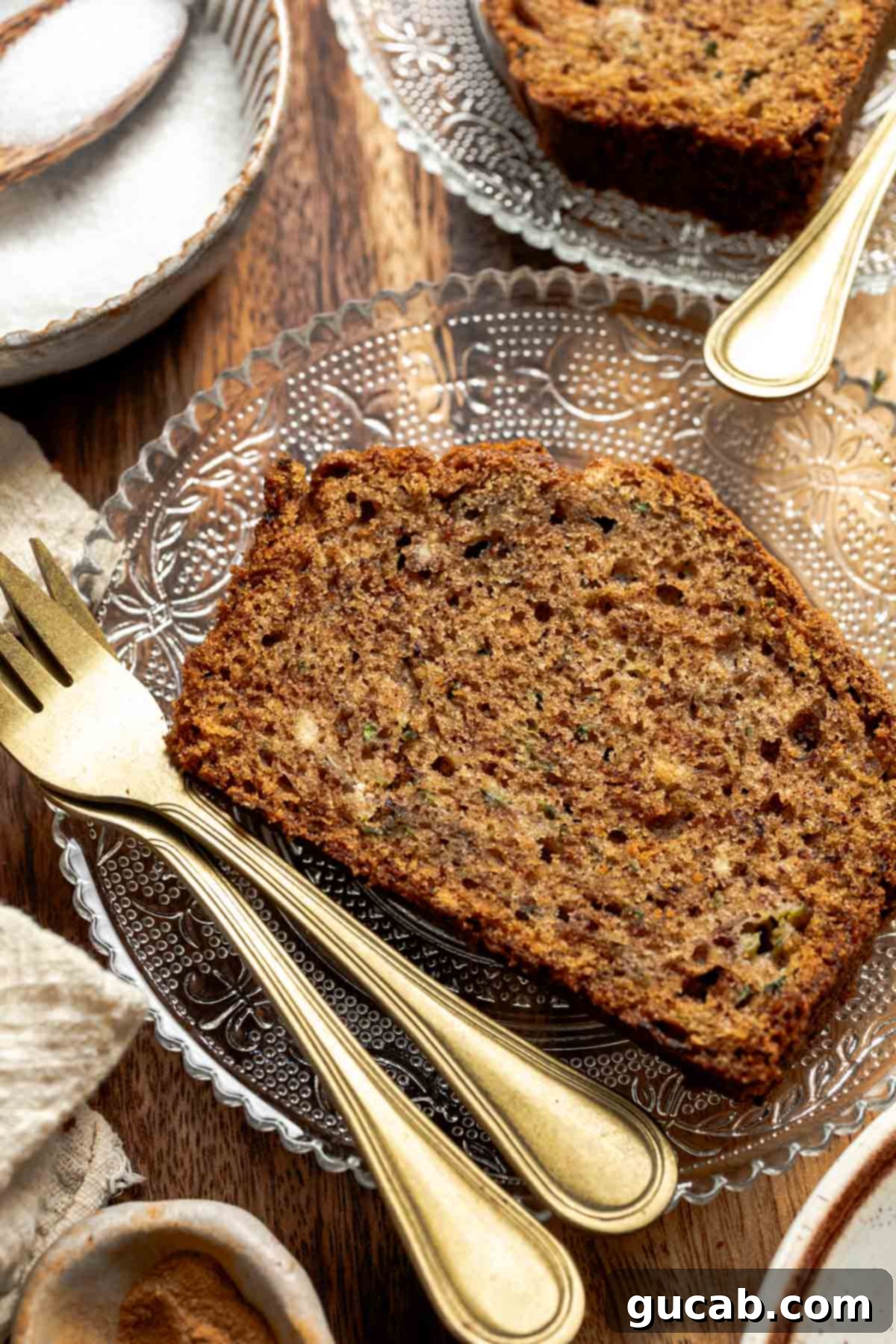 A perfectly sliced piece of moist gluten-free zucchini bread, showcasing its soft texture and subtle green flecks, resting on a white plate ready to be enjoyed.