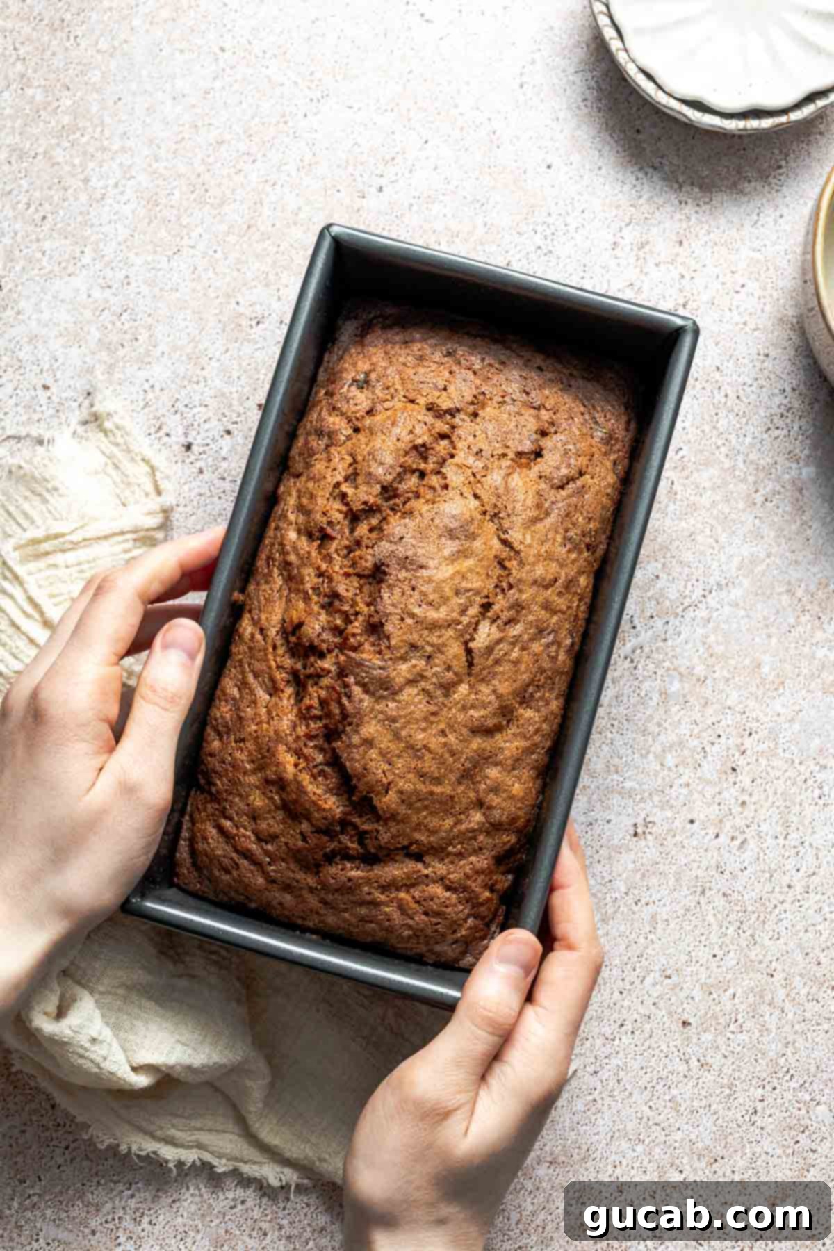 A freshly baked loaf of golden-brown gluten-free zucchini bread, perfectly risen in its pan, removed from the oven and cooling.