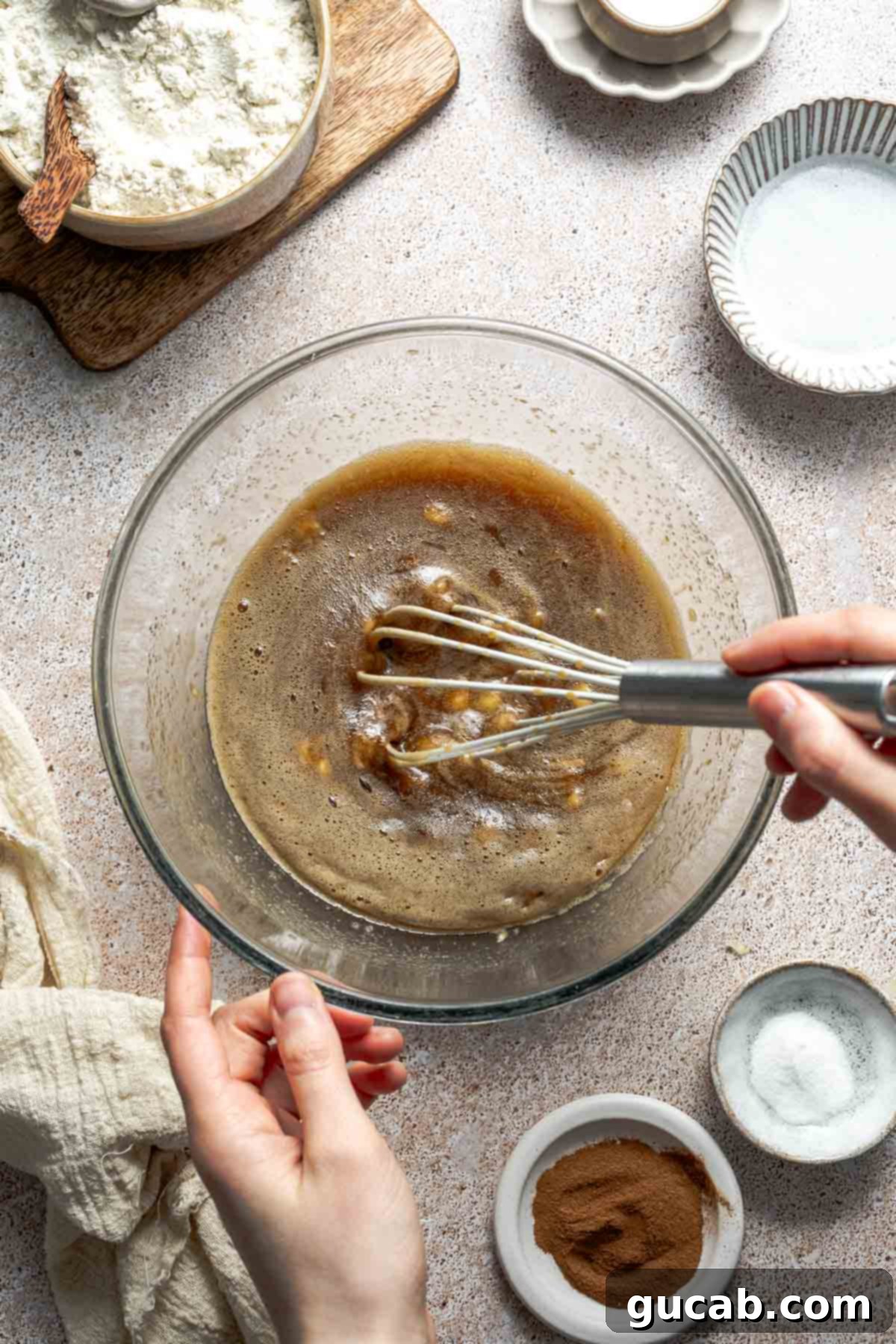 Close-up shot of the wet ingredients being whisked together in a bowl, creating a smooth and uniform mixture for the zucchini bread batter.