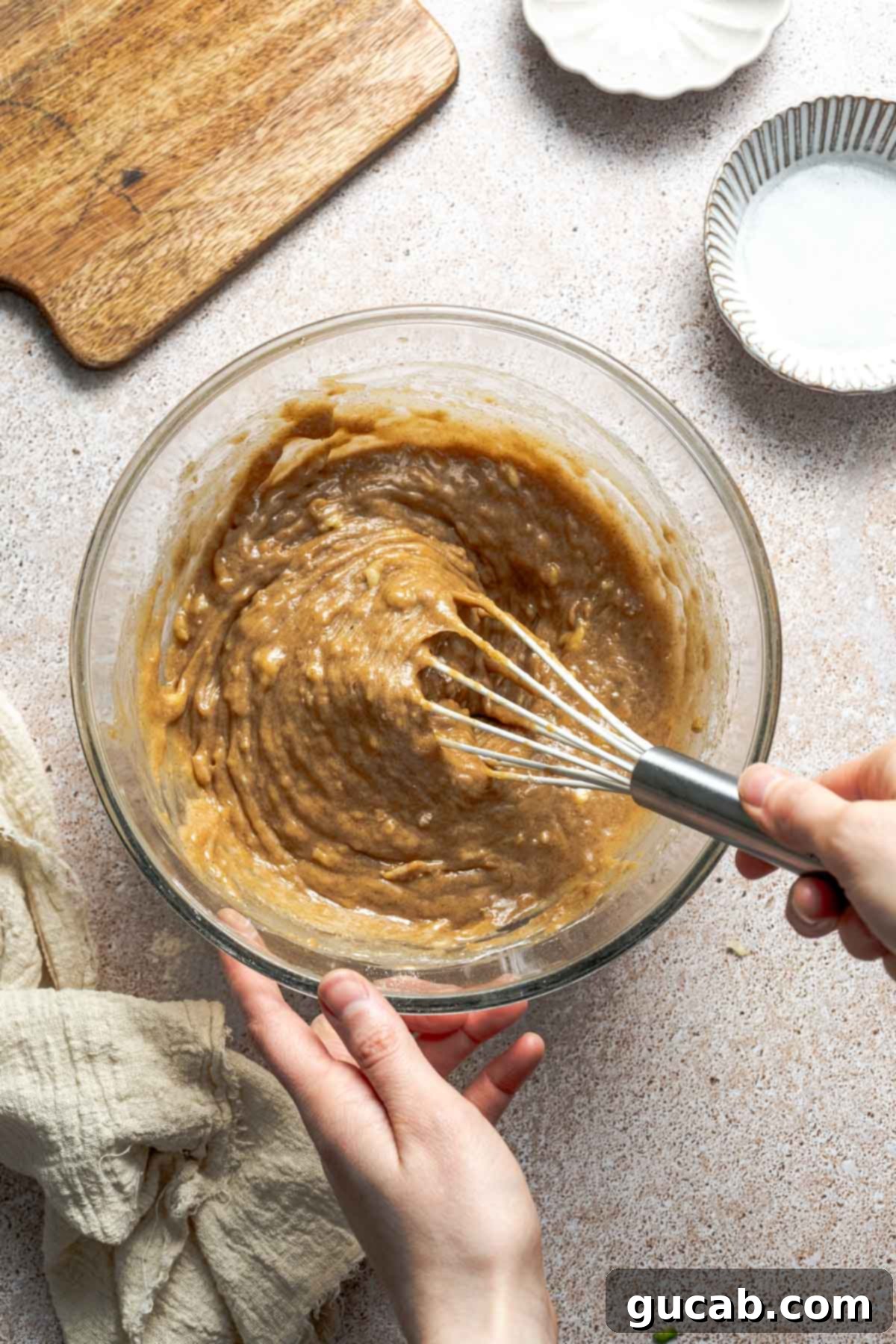 A bowl of gluten-free zucchini bread batter being gently whisked to combine the dry and wet ingredients until smooth.