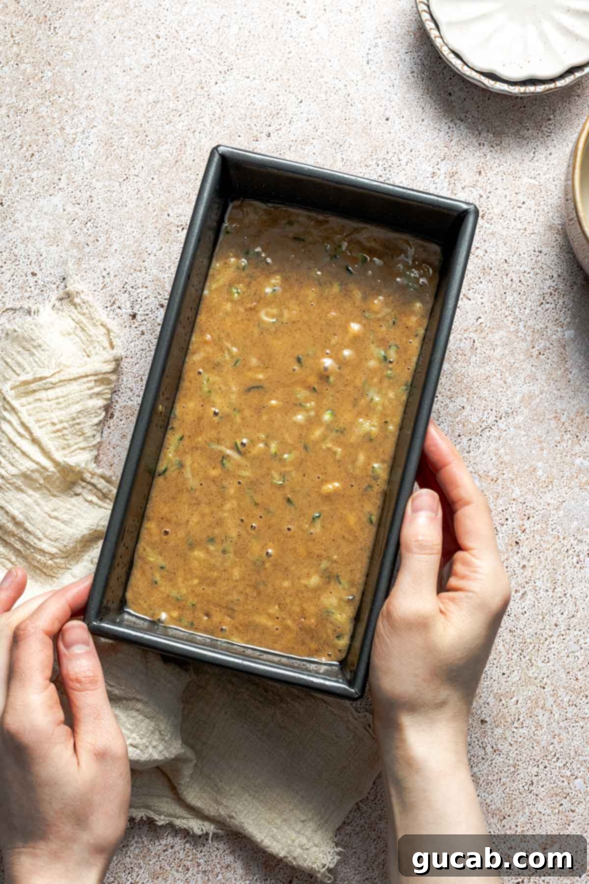 Gluten-free zucchini bread batter, rich with shredded zucchini, poured into a greased loaf pan, ready for baking.