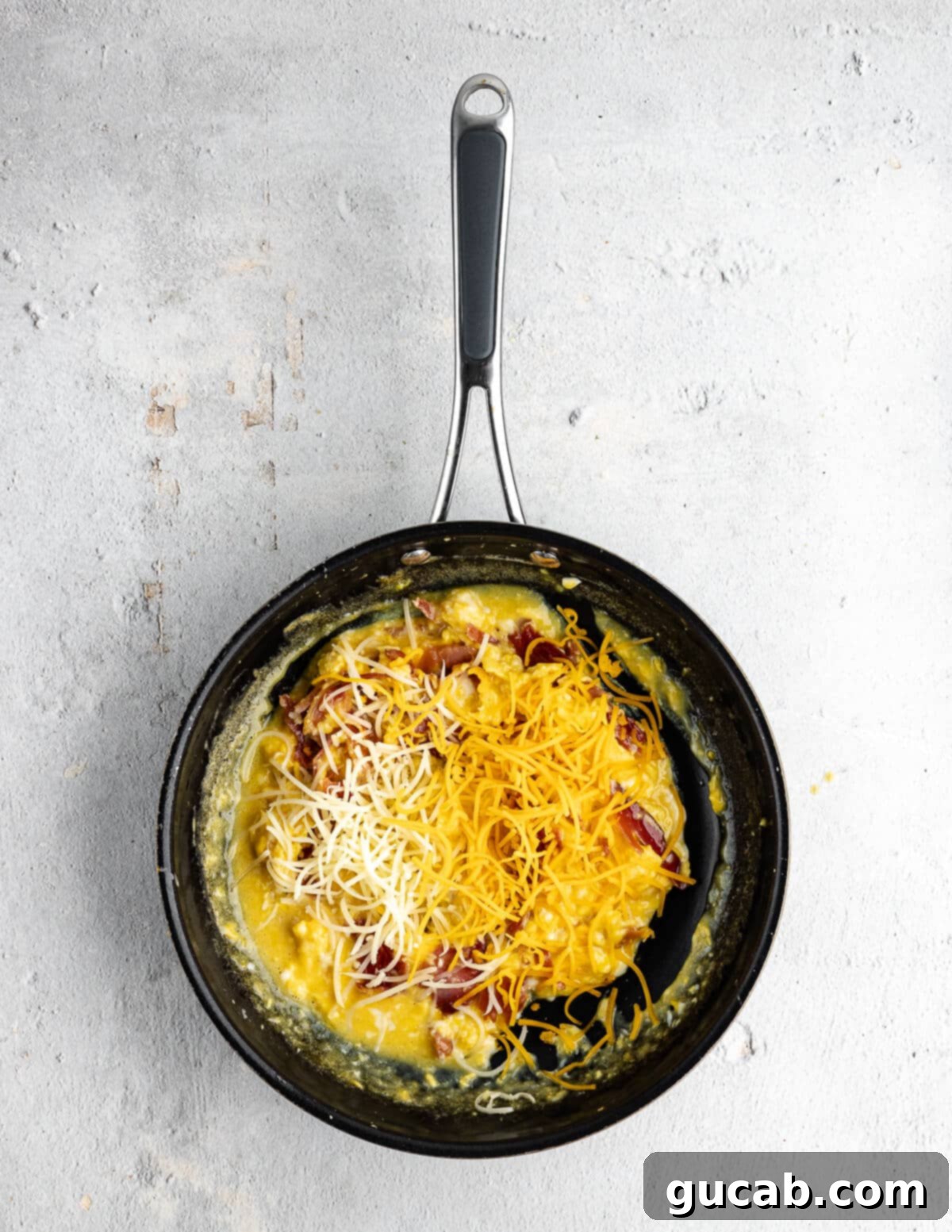 Savory Prosciutto & Cheese Scramble 12 Scrambled eggs in a skillet with shredded cheddar cheese sprinkled on top, just starting to melt.