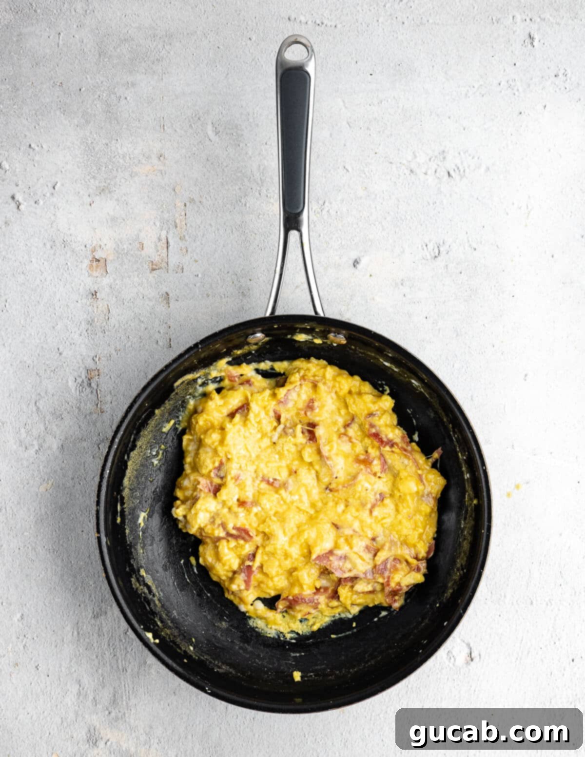Savory Prosciutto & Cheese Scramble 13 Fully cooked cheesy scrambled eggs in a skillet, still moist and fluffy.