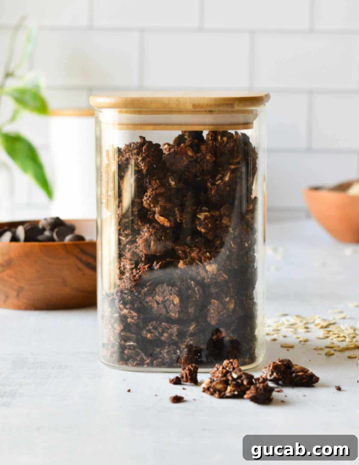 Dark Chocolate Granola 2 A beautiful glass container filled to the brim with generous dark chocolate granola clusters, showcasing their rich color and inviting texture.