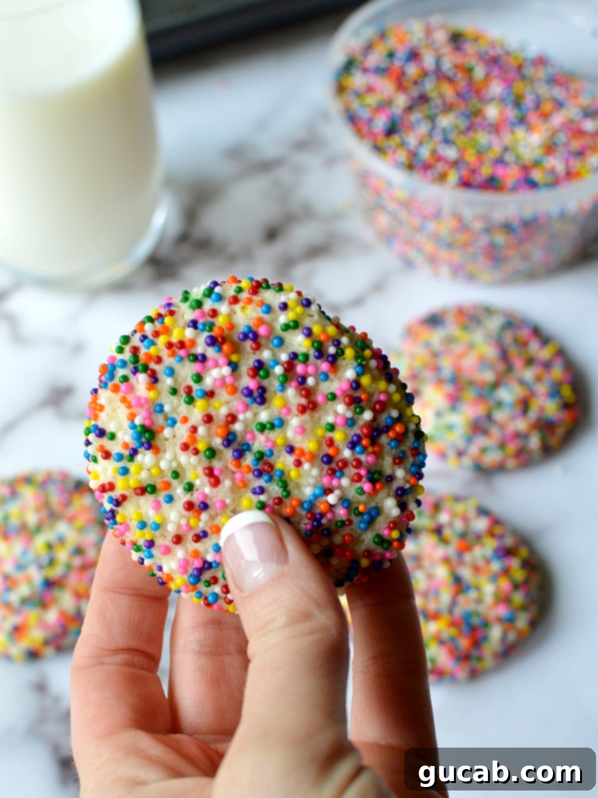 A hand holding several bright and cheerful gluten-free sprinkle cookies, ready to be enjoyed.