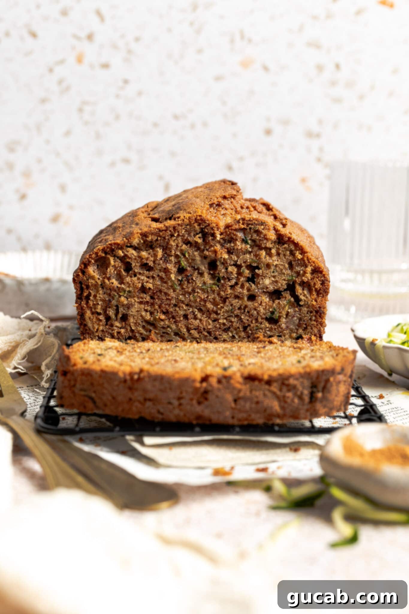 A fresh loaf of gluten-free zucchini bread with a slice cut, showing its moist interior.