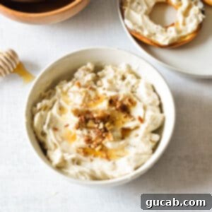 A bowl of honey walnut cream cheese topped with extra walnuts and a drizzle of honey, emphasizing its deliciousness.