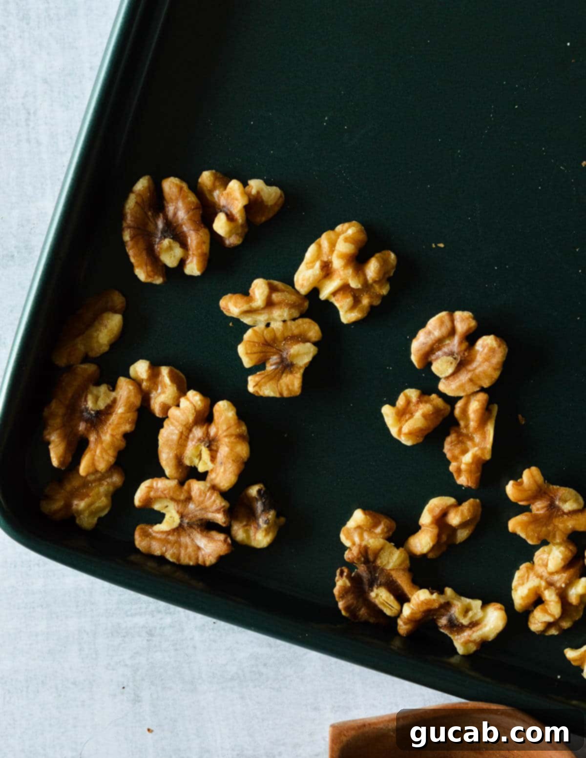Raw walnuts are evenly spread on a baking sheet, ready for toasting.