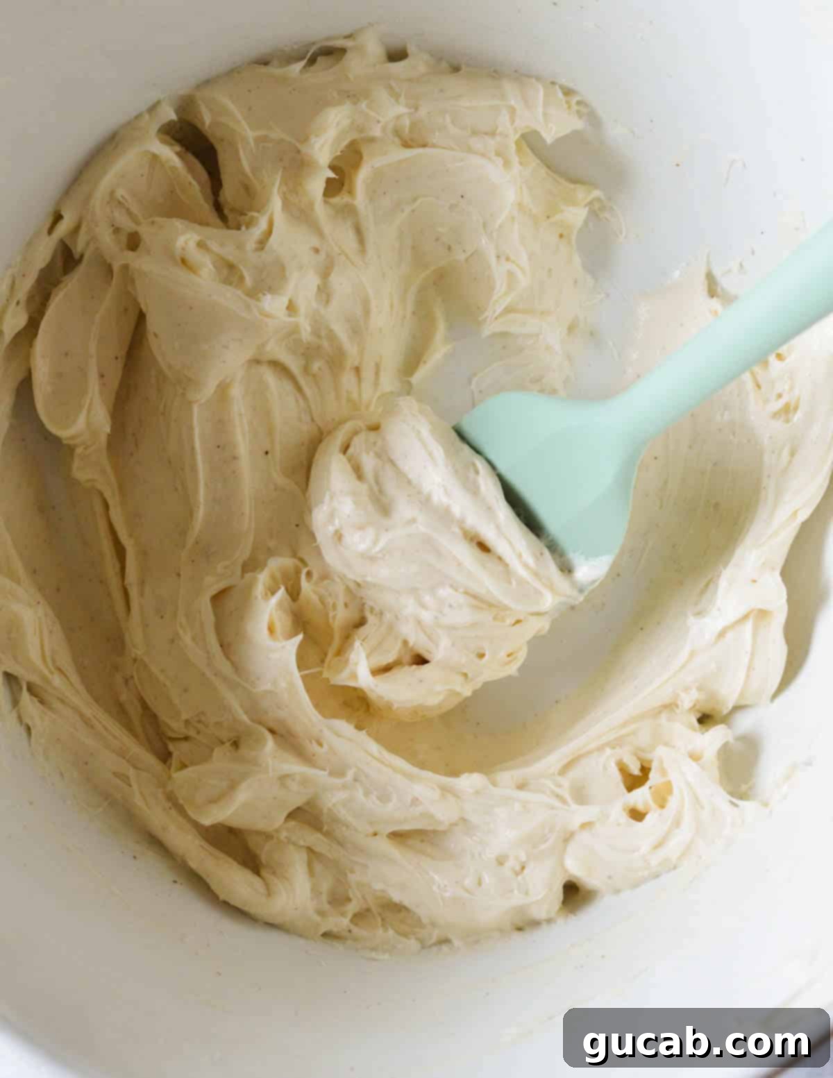 The honey cream cheese mixture, now smooth and whipped, in a bowl after being combined with a hand mixer.