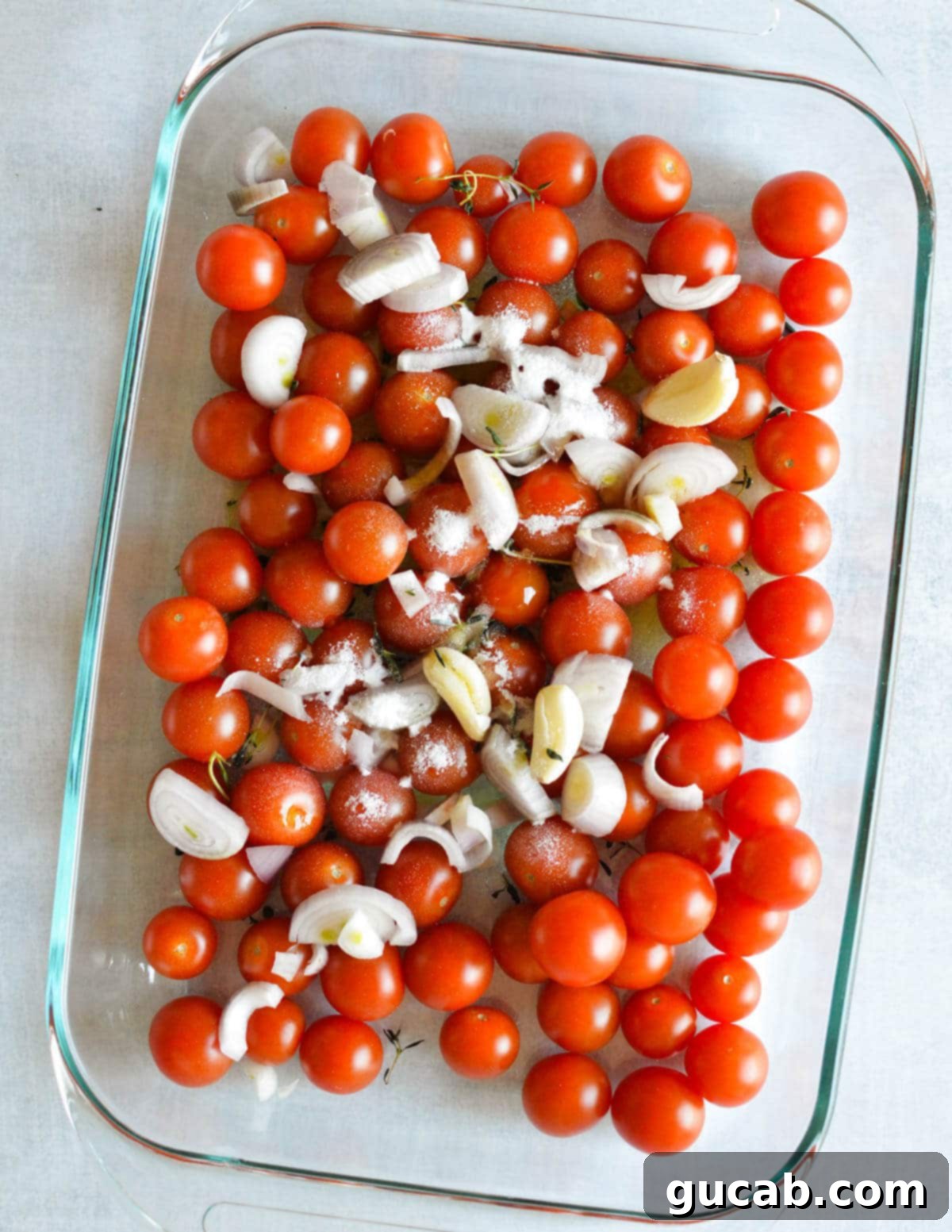 Cherry Tomato Soup 4 Fresh cherry tomatoes, whole garlic cloves, and sliced shallots with olive oil, sugar, and thyme leaves prepped in a glass baking dish, ready for roasting.
