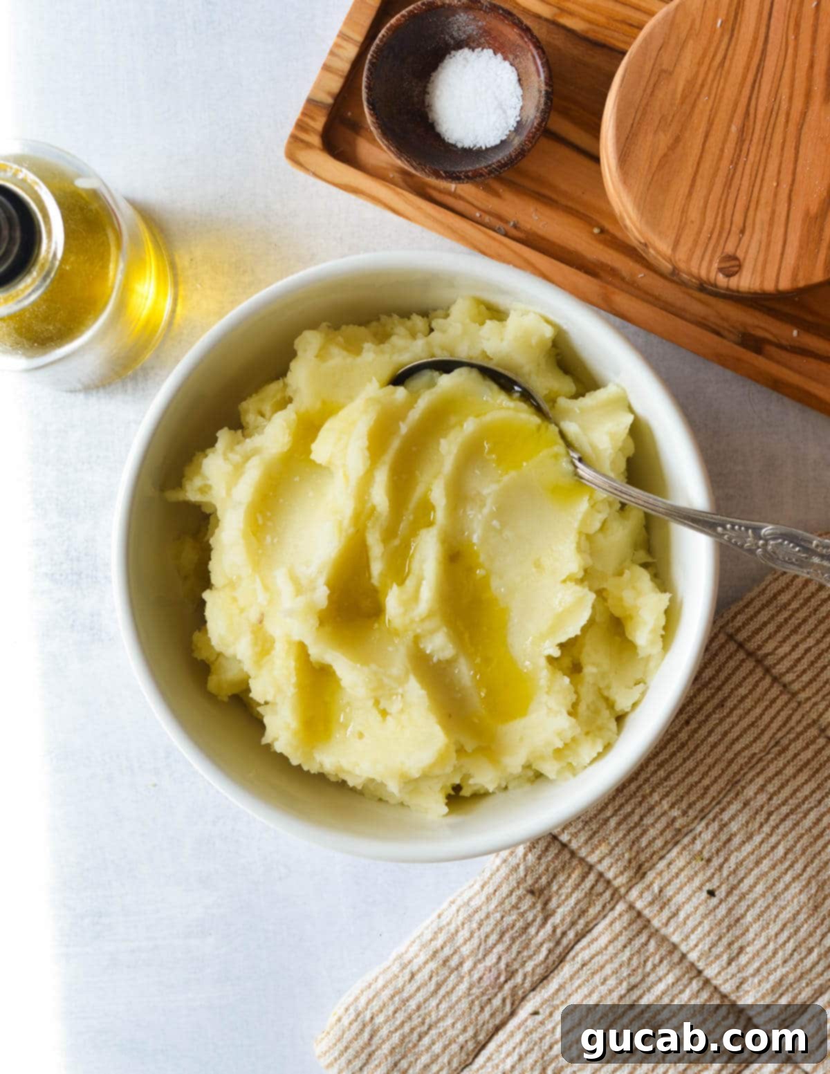 A beautifully presented bowl of creamy olive oil mashed potatoes, topped with a fresh drizzle of olive oil and a sprinkle of salt.