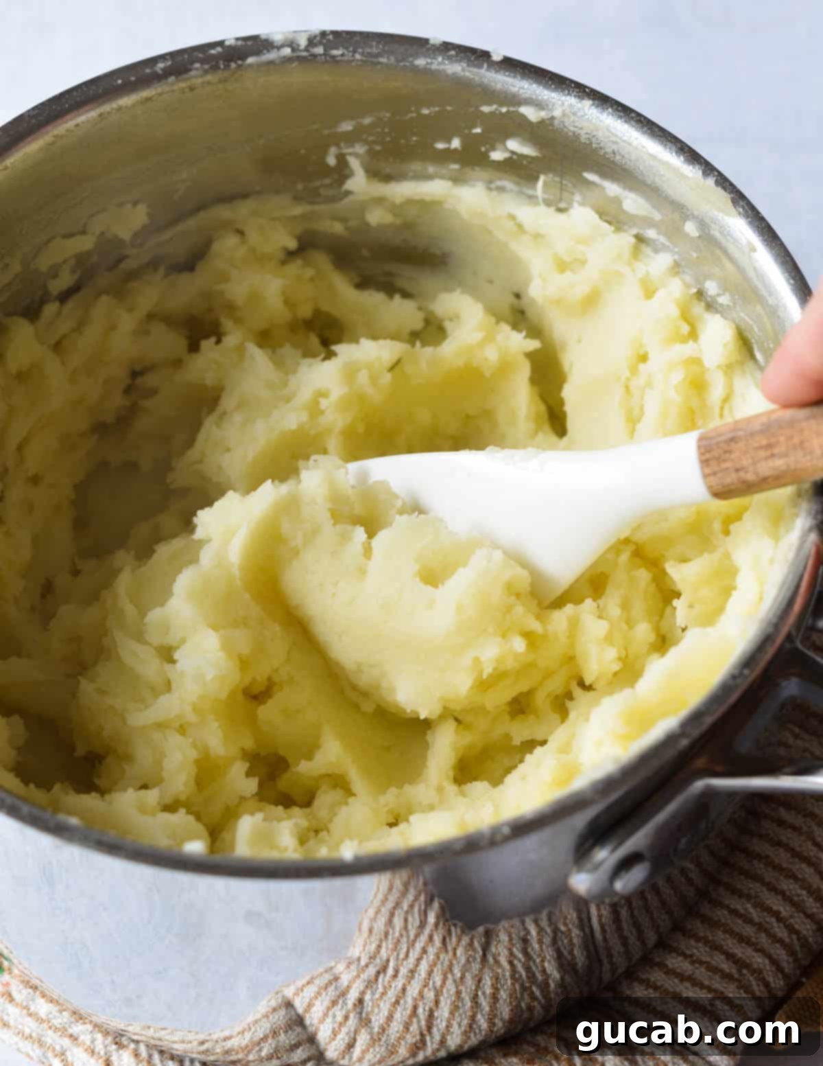 A pot of mashed potatoes, being mixed with a hand mixer to achieve a smooth and creamy texture.