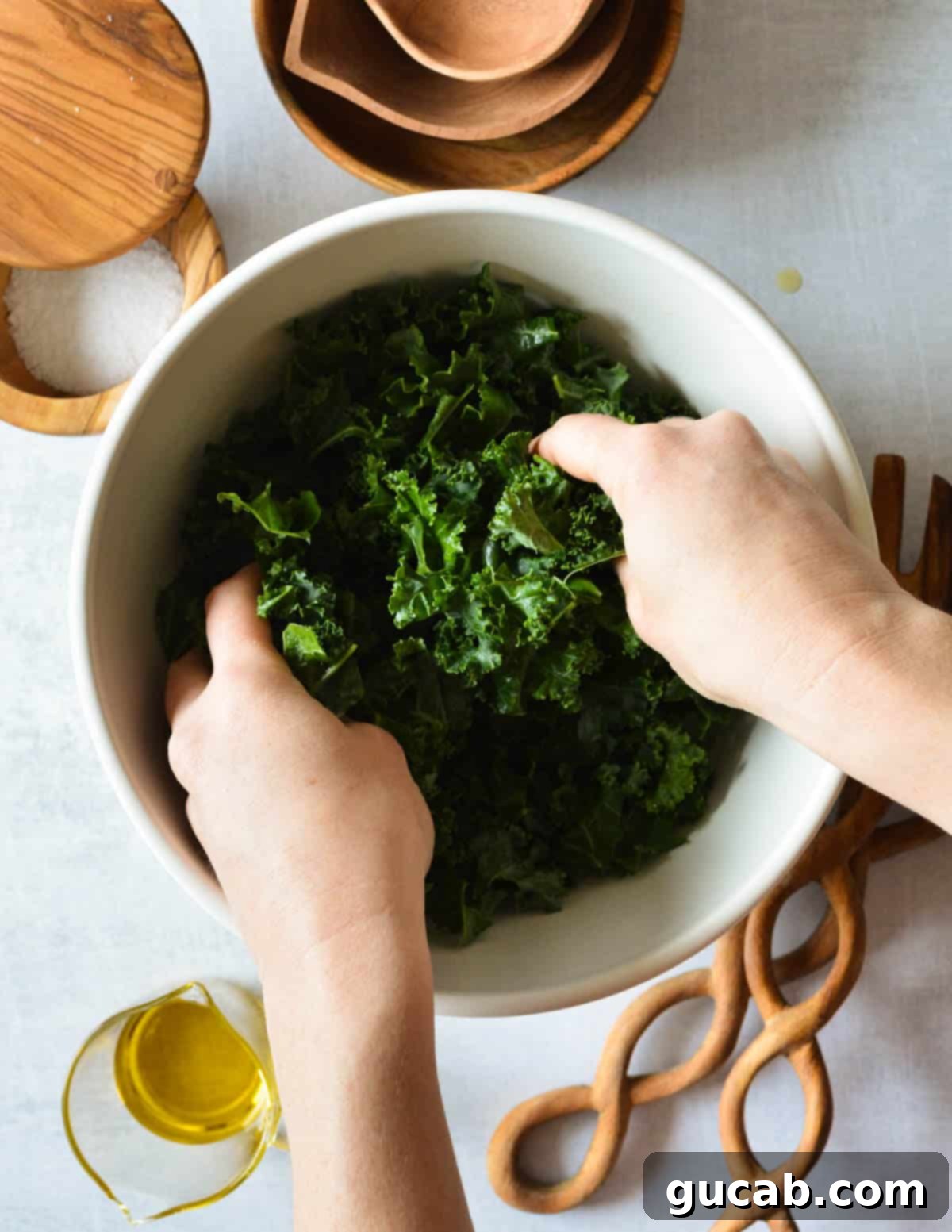 Kale Crunch Salad 6 hands massaging kale leaves with oil on them.