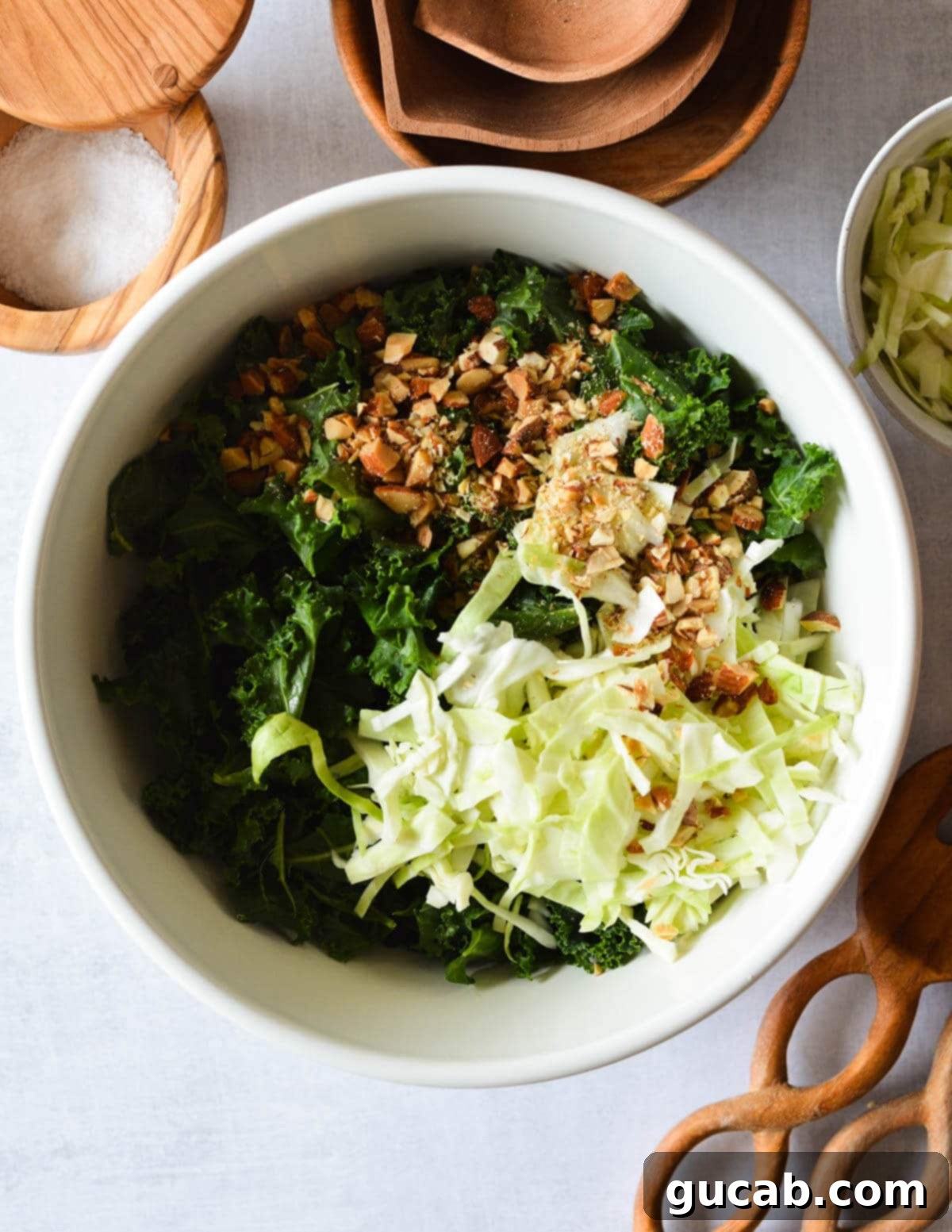 a bowl of kale with chopped almonds and shredded cabbage on top. 