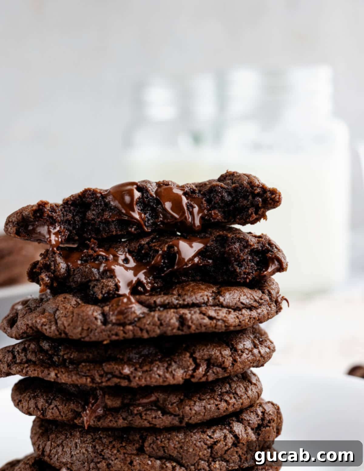 A stack of warm, gooey triple chocolate cookies with melted chocolate oozing out, inviting a delicious bite.