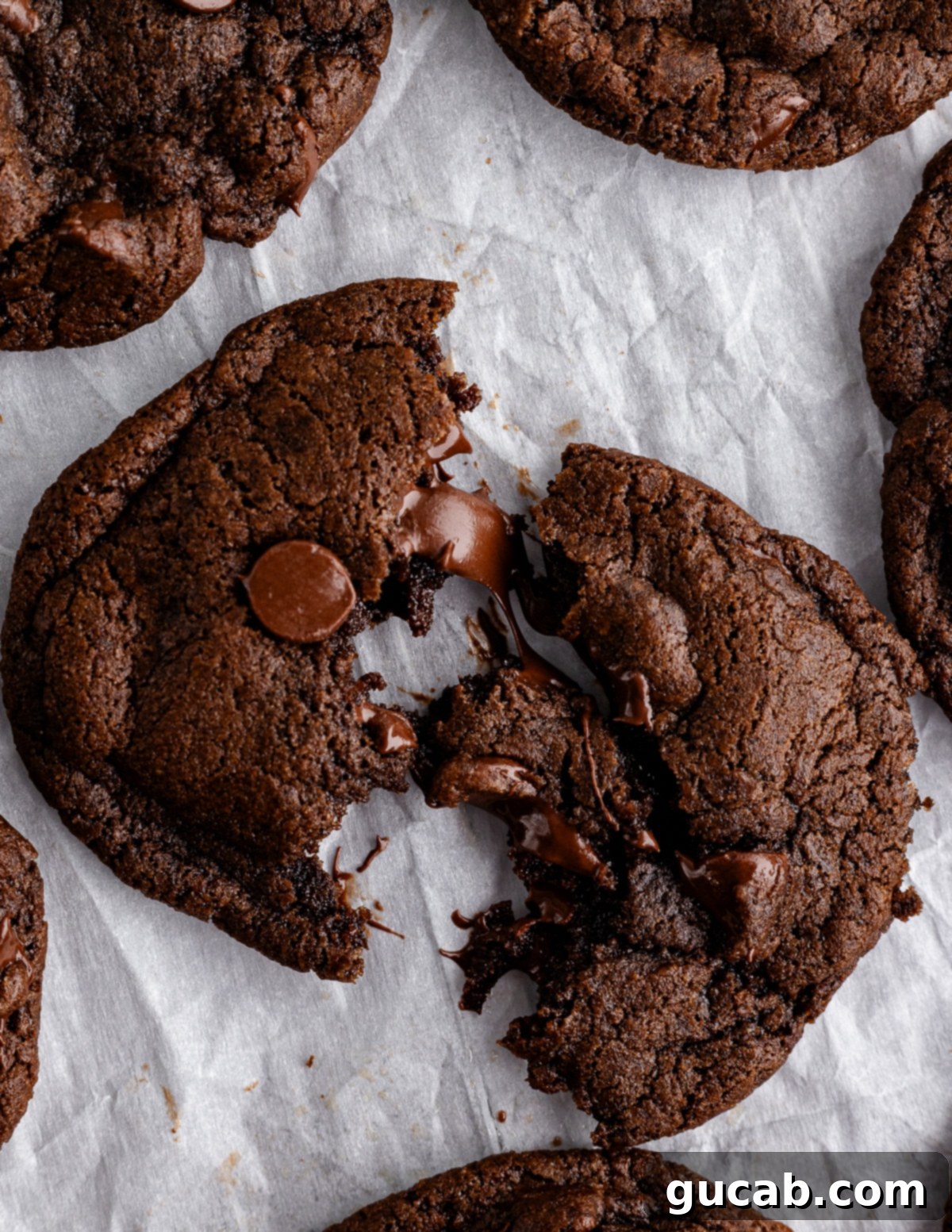 A perfectly broken triple chocolate cookie, showcasing its moist, fudgy interior and melted chocolate chips.