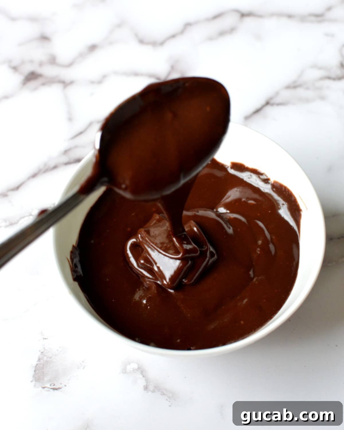 a spoonful of chocolate ganache being lifted from a bowl