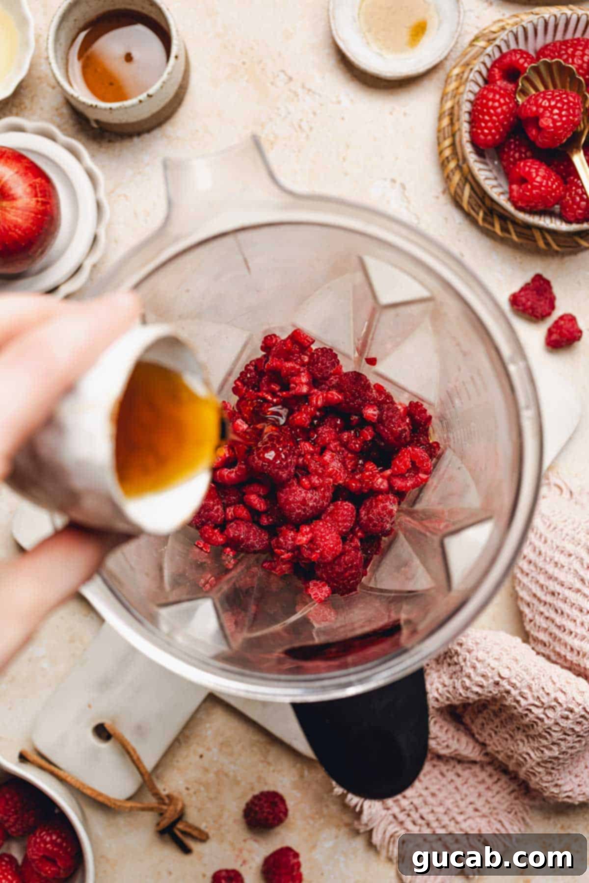 The raspberry sorbet mixture in a blender, being scraped down with a spatula to ensure even blending.