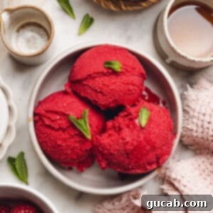 A bowl with scoops of raspberry sorbet with mint leaves on top, ready to serve.