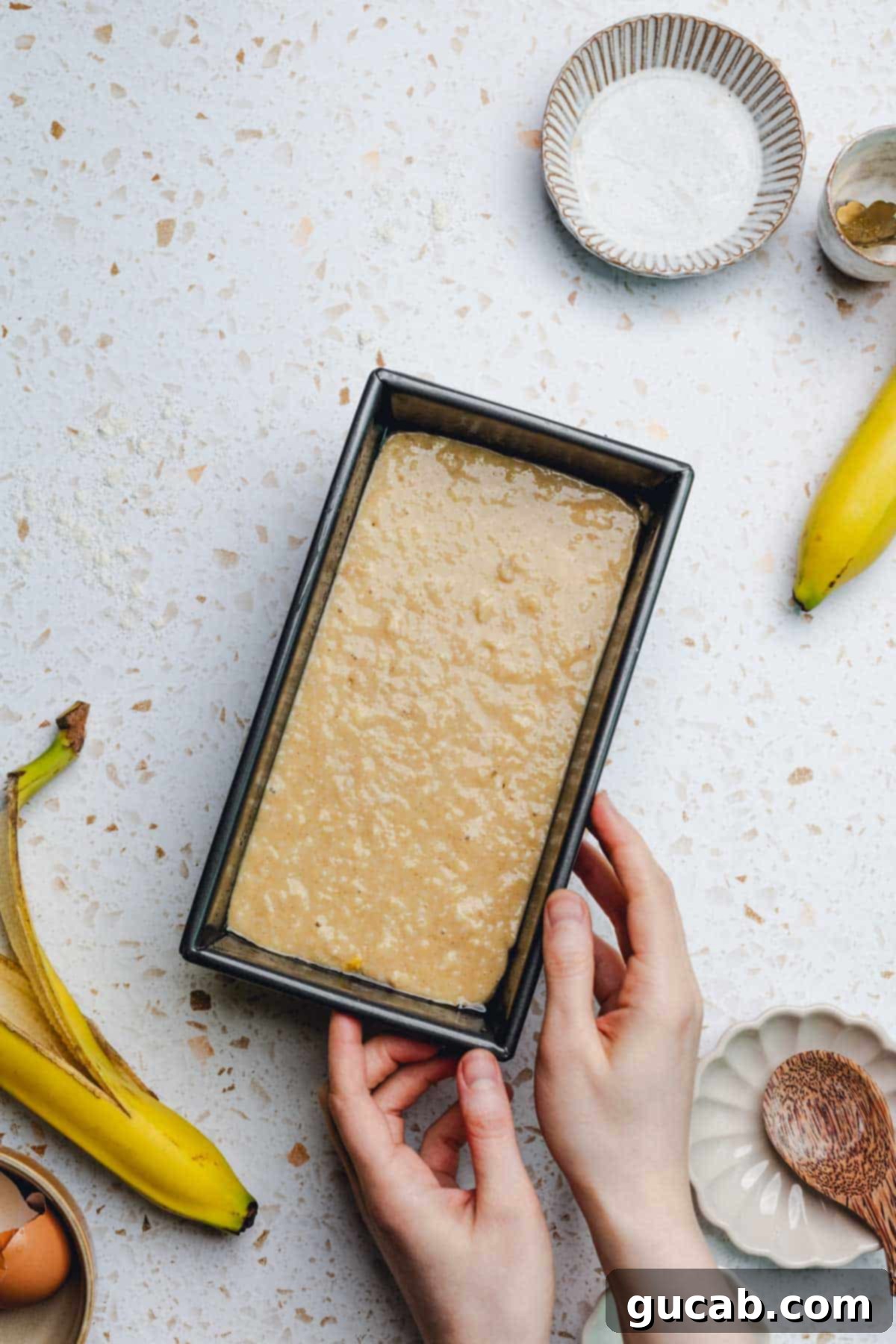 Thick honey banana bread batter evenly distributed in a greased loaf pan, ready for the oven.