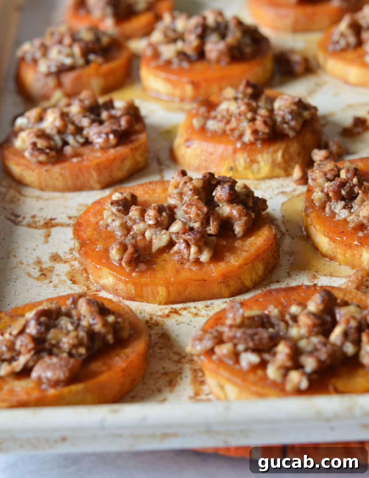 Close-up of roasted sweet potato slices topped with candied pecans, glistening and ready to serve.