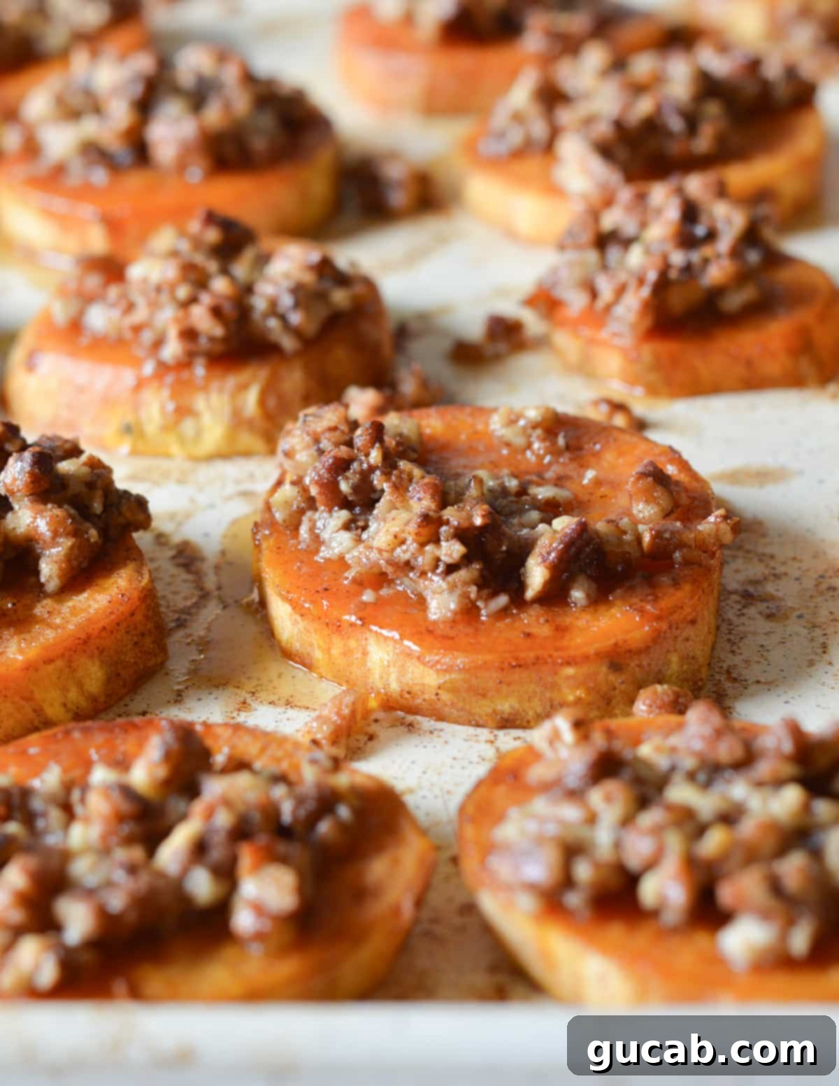 Serving platter showcasing freshly roasted sweet potato slices, each beautifully adorned with crispy candied pecans.