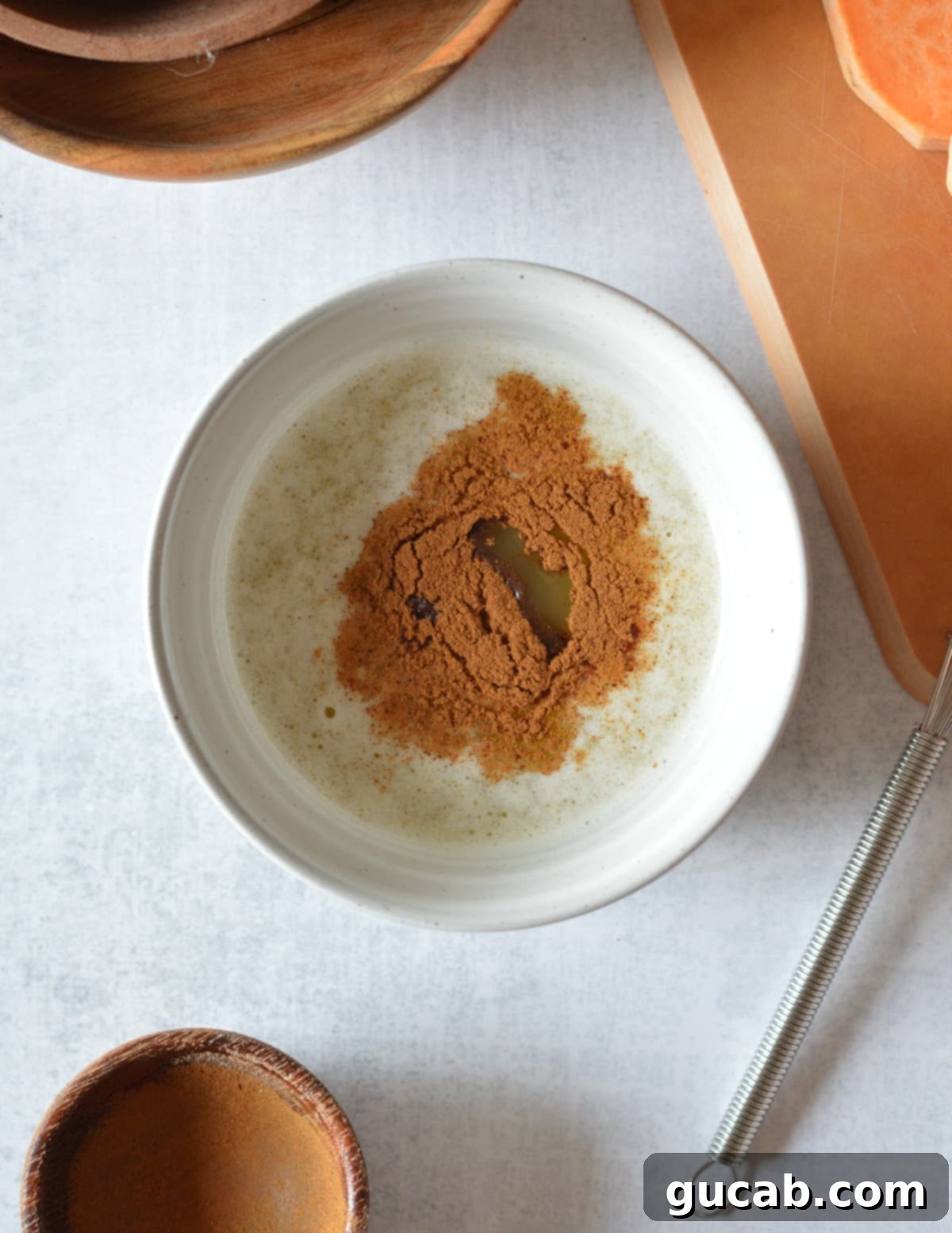A small bowl containing melted butter, maple syrup, and ground cinnamon, perfectly mixed.
