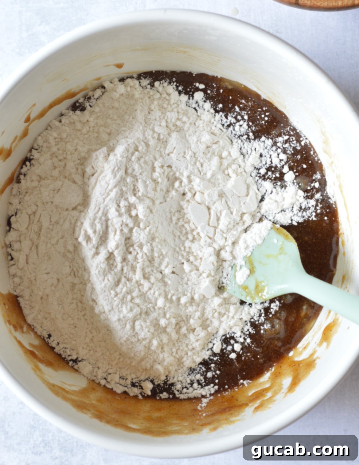 a bowl of sugar, butter, and eggs mixed together with gluten-free flour on top.