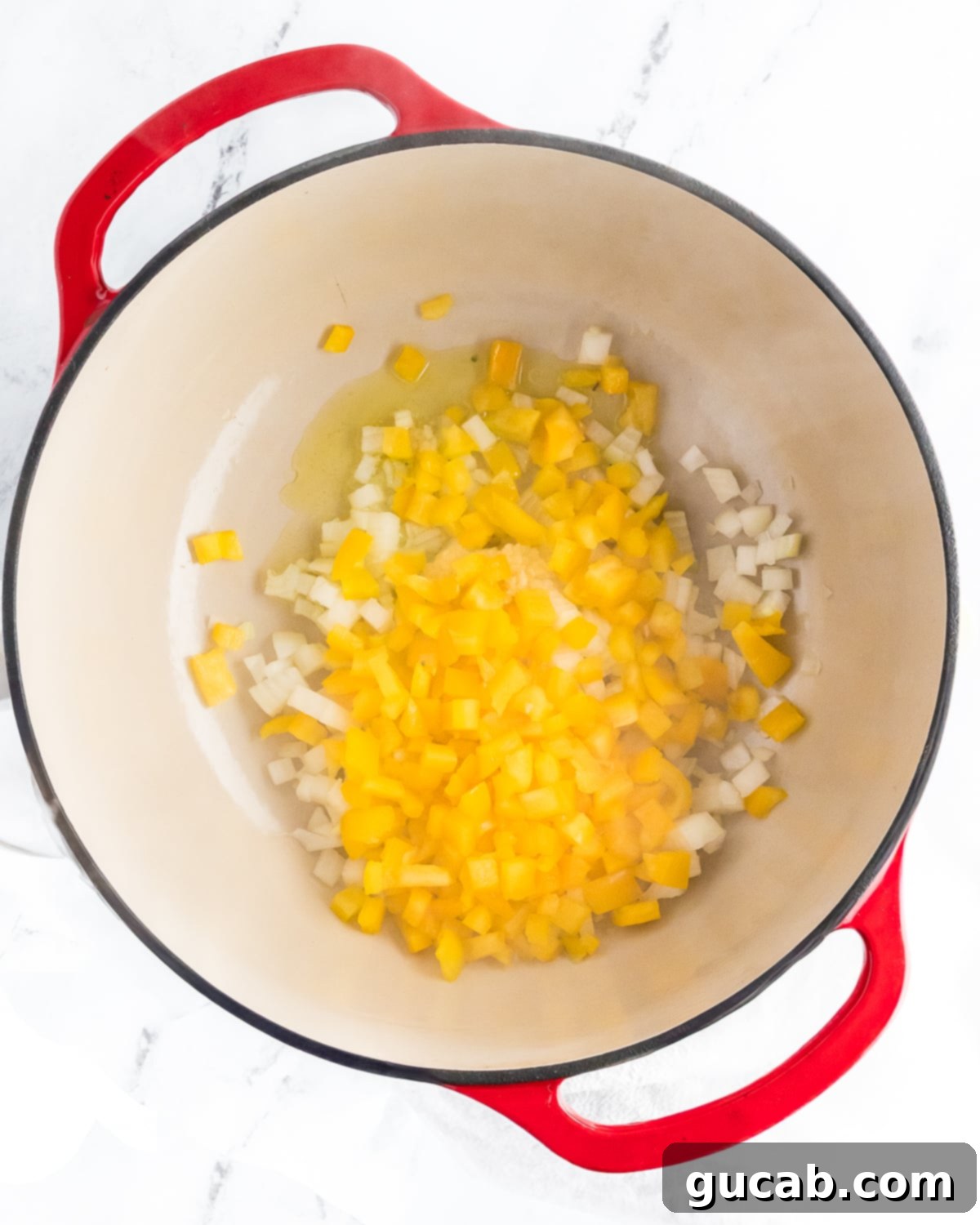 Creamy White Ground Chicken Chili 5 Yellow bell pepper, diced onion, and olive oil sautéing in a Dutch oven.