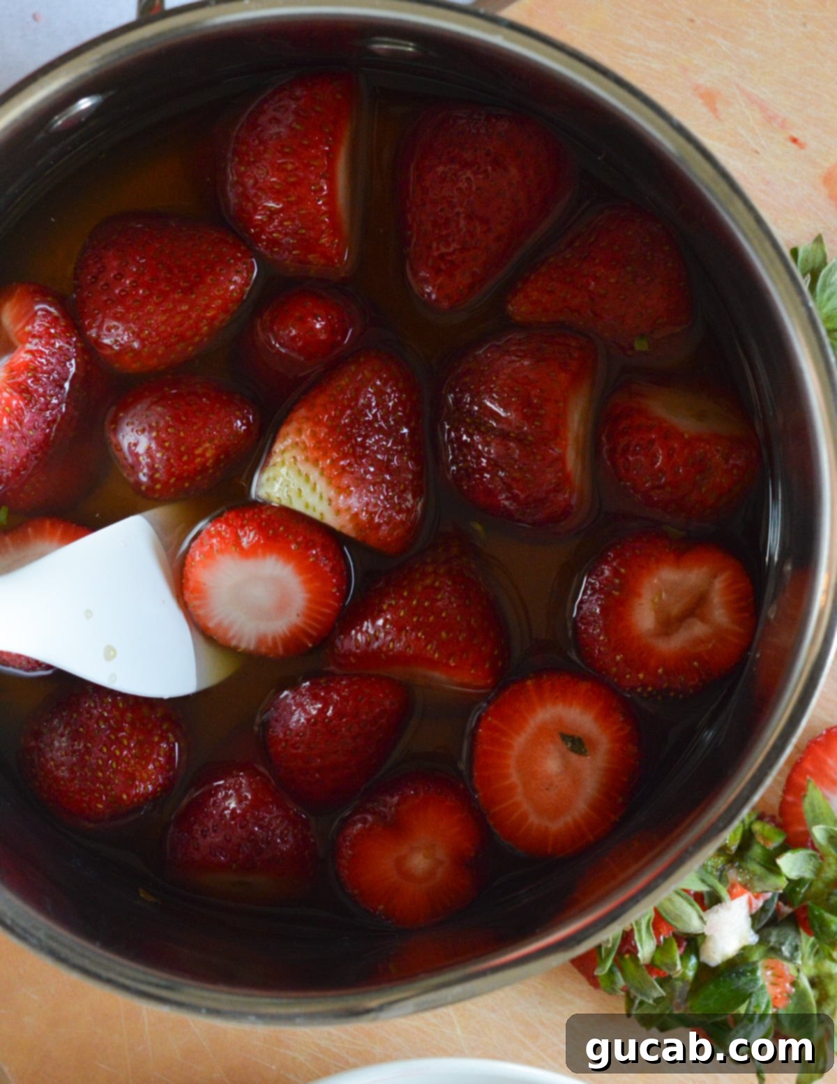 Raw strawberries, passion fruit juice, and maple syrup are combined in a saucepan, beginning the process of making delicious homemade popsicles.