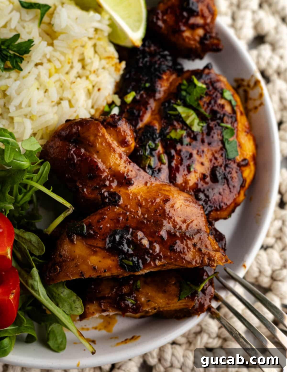 Honey chipotle chicken thighs served on a plate with fluffy white rice and a fresh green salad, garnished with lime wedges.