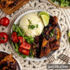 Plate of honey chipotle chicken thighs served with rice and tomatoes.
